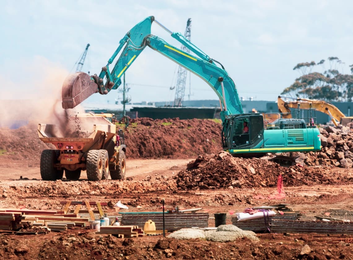 An excavator loading a haul truck on a graded pad